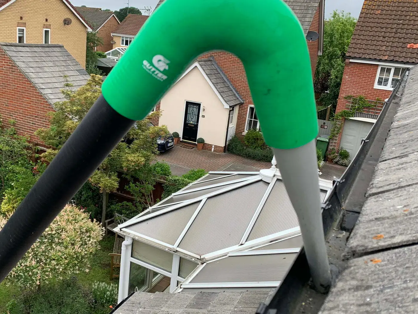 Gutter vacuum pole reaching over a roof to clear guttering from ground level